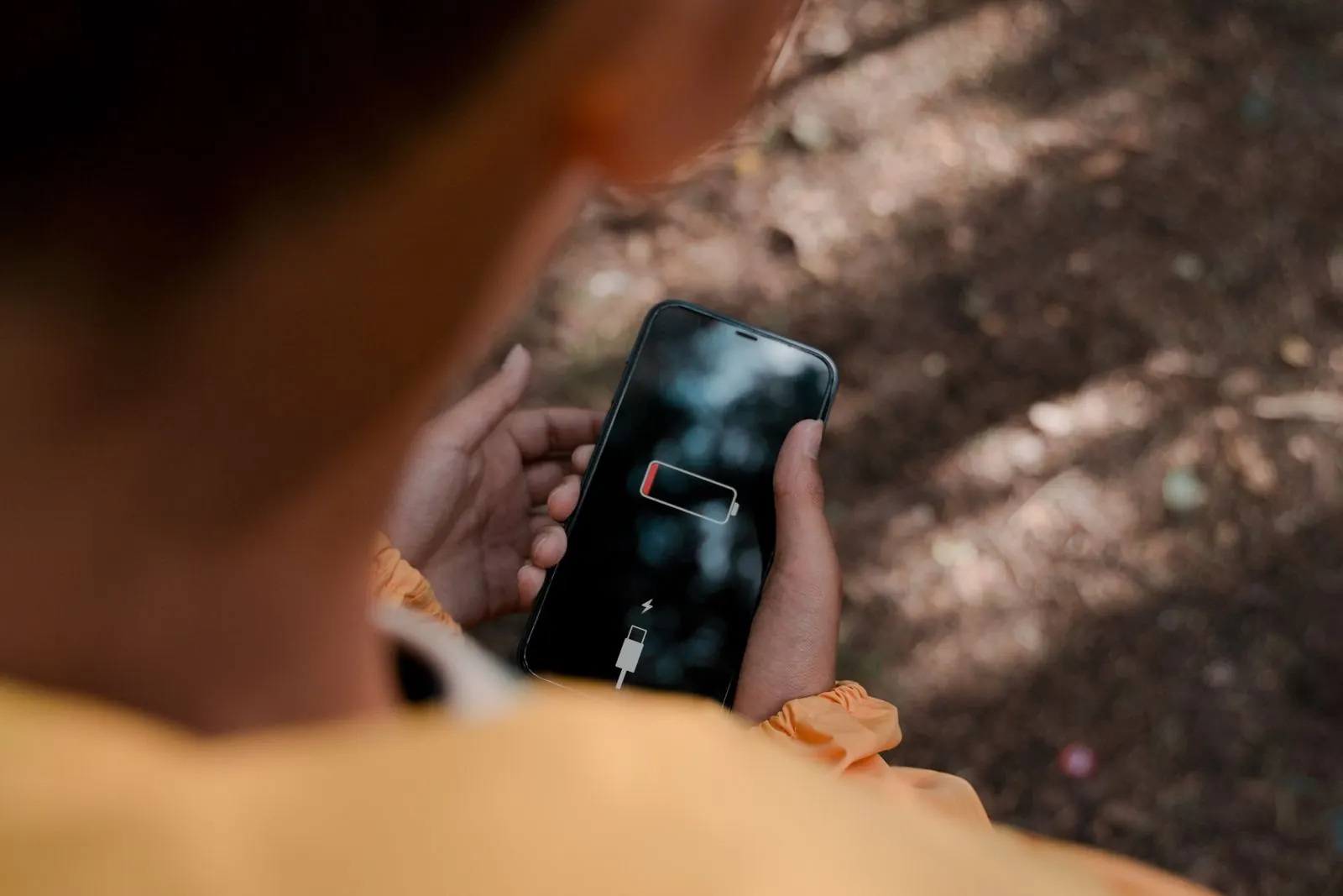 Téléphone affichant une batterie faible, tenu à la main